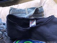 Black sweater with Seattle Seahawks logo and Jerzees NB Blend tag on collar showing size XL, lying over denim jeans.