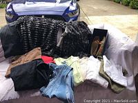 Photo showing multiple women's clothing items including pants, shirts, and skirt displayed on a surface.