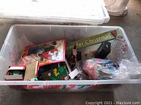Plastic bin filled with various Christmas decoration items, ribbons, and a serving platter.
