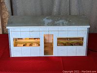 Front view of white wooden boxcar dollhouse with windows revealing detailed interior diner scene.