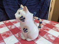 Side view of porcelain cat pitcher showing shape and blue painted accents