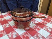 Side view of Pyrex Corning Visions double boiler set with amber glass material, showing bottom and top pots along with the lid in place.