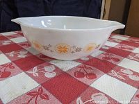 Side view of Pyrex bowl showing orange and yellow floral and geometric pattern on white glass