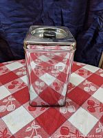 Front view of stainless steel flour canister with embossed 'FLOUR' lettering, showing reflective polished surface and black knob lid.