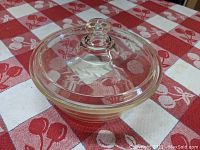 Side angle of casserole with clear glass lid showing etched rose patterns on lid and knob.