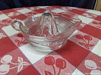 Side angle view of the glass citrus juice reamer showing the ribbed bowl, handle, and spout.