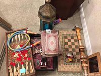 Two wooden backgammon sets, one broken with missing contents, along with a hanging lantern, small toy doll, decorative wooden boxes, tray, and board game surfaces.