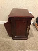 Side view of the wooden end table showing cabinet door and attached magazine rack panel