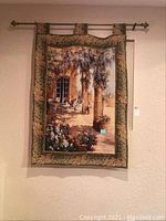Full view of wall tapestry hanging with metal rod and ornamental finials, showing patio scene with chairs, columns, plants.