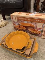 Photo of the boxed ceramic bakeware set along with the scalloped pie plate and other dishes stacked with cardboard separators.