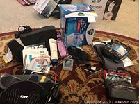 Top-down view showing Vicks mini humidifier in box, various personal care items including creams, spray, eyeglasses, and exercise equipment on carpet