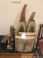 Four vases including tallest 24 inches, two bronze-tone statues, two square wall art pieces with leaf designs in front of wall