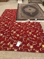 Two area rugs next to each other on a carpeted floor showing their colors and patterns.