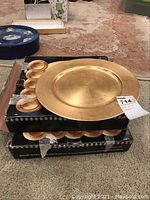 Stack of gold charger plates on top of black boxes showing the plate face and edge.