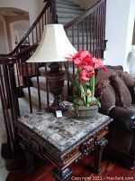 Both items shown together on a marble-topped wooden side table next to a staircase and brown couch.