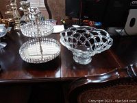 Photo showing two tier glass cupcake stand with silver center post and hand blown clear art glass bowl with lattice design on wooden table