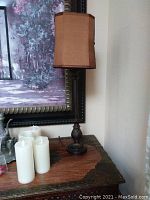 Full view of one table lamp showing brown fabric lampshade and upper base design.
