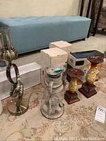 Photo showing metal swirl candle holder, vintage lantern candle holder, two boxes likely containing other candle holders