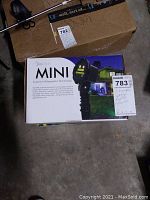 Photo showing the first Bliss Lights Mini holographic display in its original box with remote visible on the packaging.