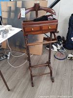 Front view of walnut valet stand with two drawers, bronze pulls, and barley twist legs.