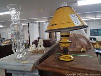 Wide view showing yellow tin tole table lamp with paper shade and nearby crystal hurricane lamp