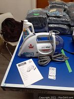 Front angle of Bissell Spot Lifter handheld cleaner with manual and partial solution bottle.