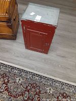 Side view of vintage metal medicine cabinet showing red painted door with paneling and silver top surface.