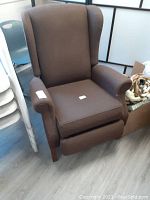 Full view of brown upholstered vintage recliner chair in upright position