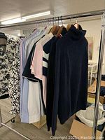 Clothing on rack including shirts and navy blue turtleneck sweater