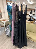 Group shot of four evening gowns hanging side by side