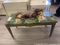 Overall photo showing rectangular table with green marble top and wooden Komodo dragon sitting on top. Shows marble pattern and brass legs.