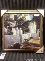 Framed painting with white building, stairway with balustrades, greenery and sunlight shadows.