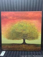 Full view of unframed canvas painting showing tree with thick green foliage against warm colored sky