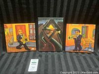 Photo of three framed plaques showing musicians, two outside with bright backgrounds and one inside with dark background.