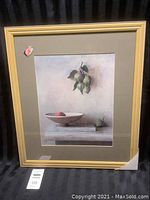 Full view of framed art print titled 'Persimmons' showing the image, matte, and frame with minor corner damage on the glass.