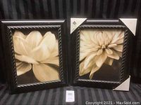 Pair of framed floral art prints side by side, each with dark carved wooden frames. Sepia tones floral images. One frame showing corner protective paper.