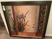 Framed art piece depicting purple irises with a decorative abstract background, showing the full artwork and frame.