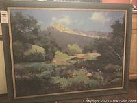 Full view of framed landscape painting showing the mountain, trees, and cloudy sky.