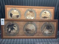 Two framed art prints shown side by side on striped fabric background. Each frame features three circular porthole-style images of sepia-toned Hawaiian scenes, mounted on wooden background with metal accents.