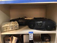 Shelf with three radios: General Electric radio (white, vintage), Sony radio and cassette player (black), and Magnavox boombox (black).