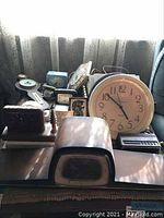 Overall view of multiple clocks including large beige wall clock and smaller tabletop clocks