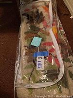 Two hooked rugs rolled and partially unfolded inside a clear plastic storage bag showing leaf patterns in autumn colors on a cream background.
