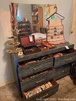 Full dresser top showing jewelry box, tiered stand, hanging pouch and drawers of loose jewelry