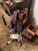 Wide angle showing collection of men's neckties on rack, shoe polishing kit, and some other accessories scattered on carpeted floor.