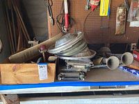 Overview of vintage car parts including the Chevy radio, multiple rusted metal parts, stacked hubcaps, and twin horn trumpet assembly.