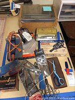 Overview photo showing Dremel engraver box, multiple scissors, homemade light box, and small jewelry cleaner kit.