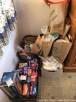 Photo showing large paper bags filled with assorted paper goods and disposables next to unopened boxes of foil and plastic bags.