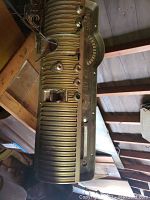 Vintage metal car dashboard showing ribbed design, integrated speedometer, multiple control knobs, and wiring on the back side.