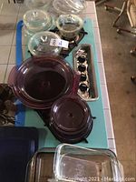 Top-down view of purple Visionware glass cookware and clear Pyrex baking dishes arranged on a table.