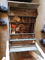 Open blue metal toolbox revealing top cantilever trays and interior compartments filled with various hardware